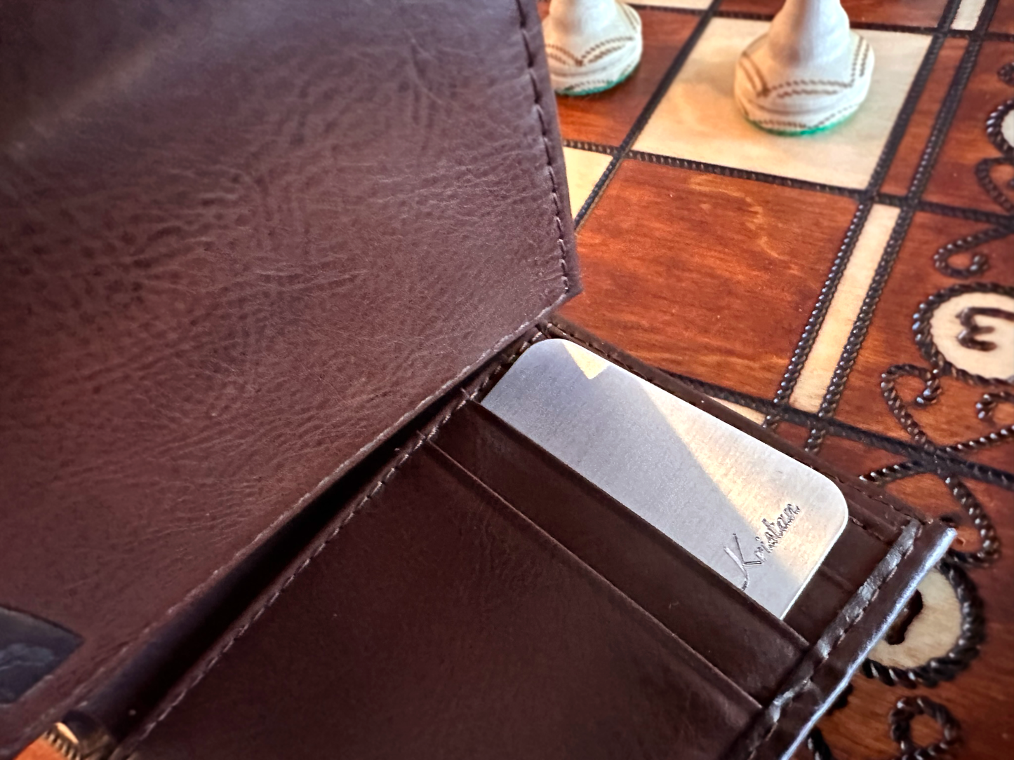 Engraved aluminum wallet card tucked into a brown leather wallet